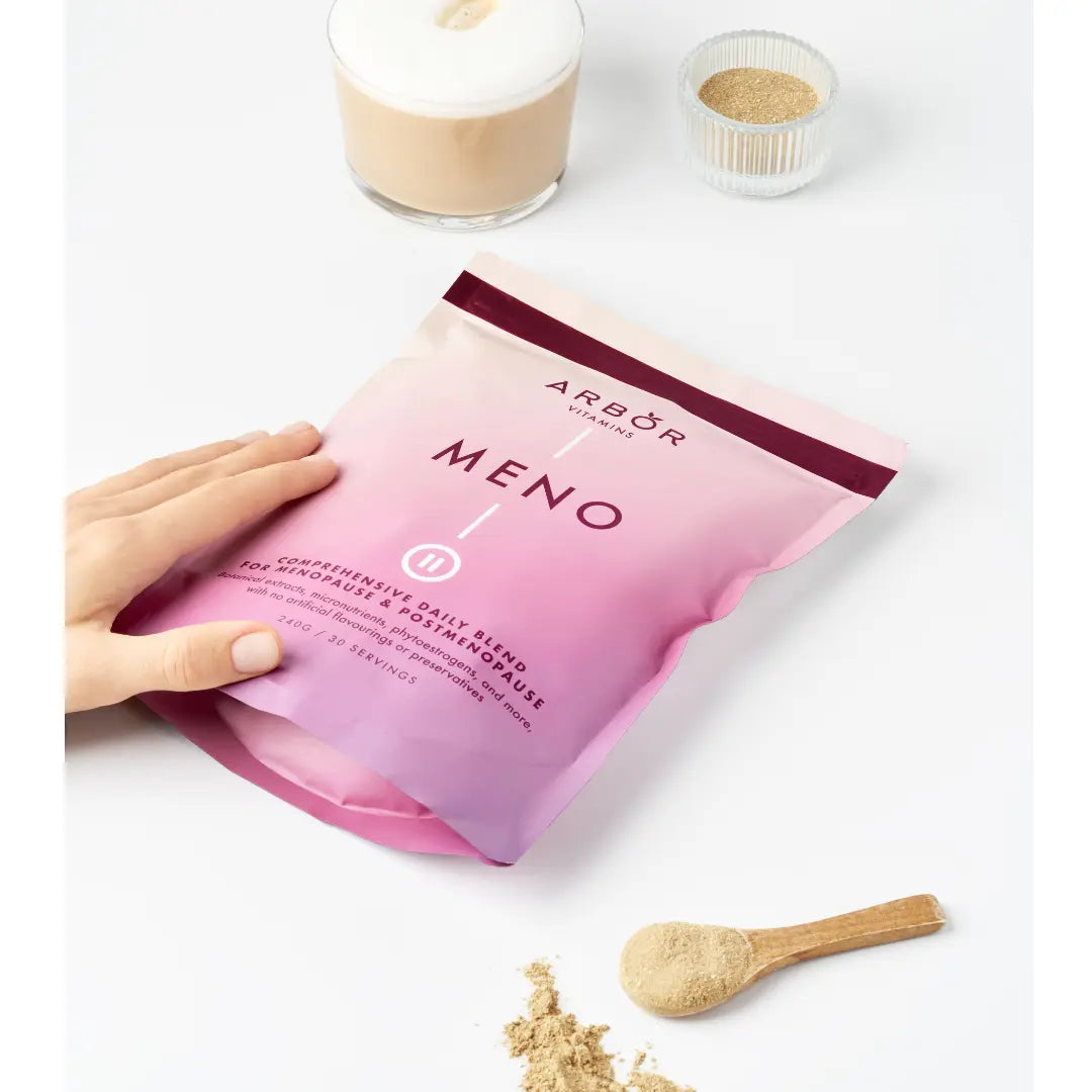 Hand holding an Arbor Vitamins MENO Blend powder pouch on a white background