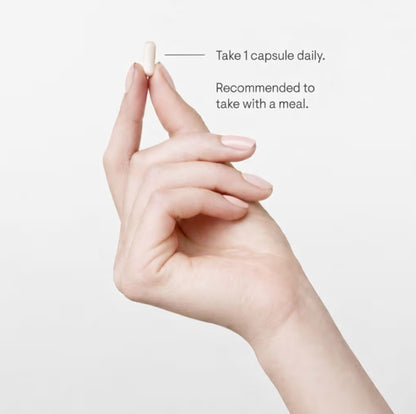 Hand holding a capsule with text on a light background